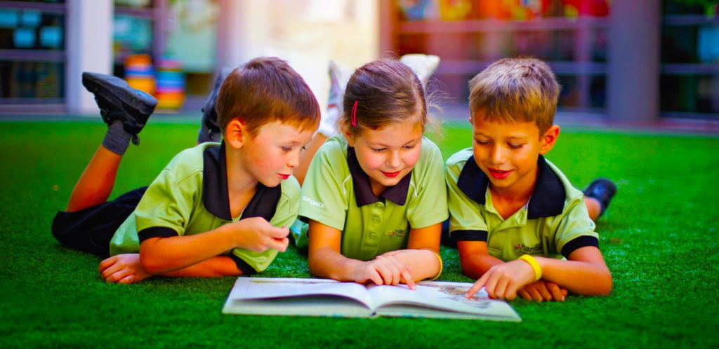 Kinder an der Hartland International School lesen im Sonnenschein von Dubai.