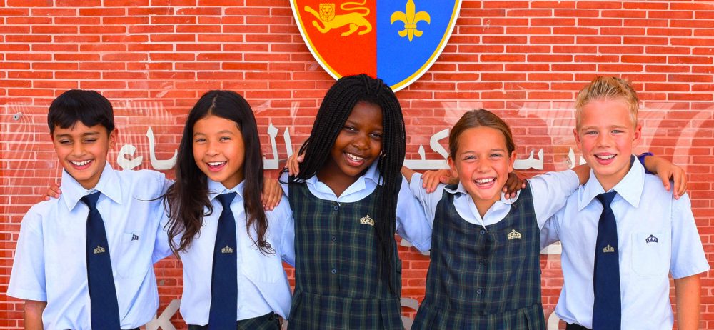 Photograph showing students at Kings' School Al Brasha undder the school's coat of arms