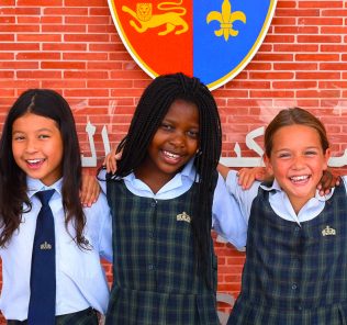 Best School in the UAE for Children of Determination at The Top Schools Awards. Photograph showing students at Kings' School Al Barsha under the school's coat of arms