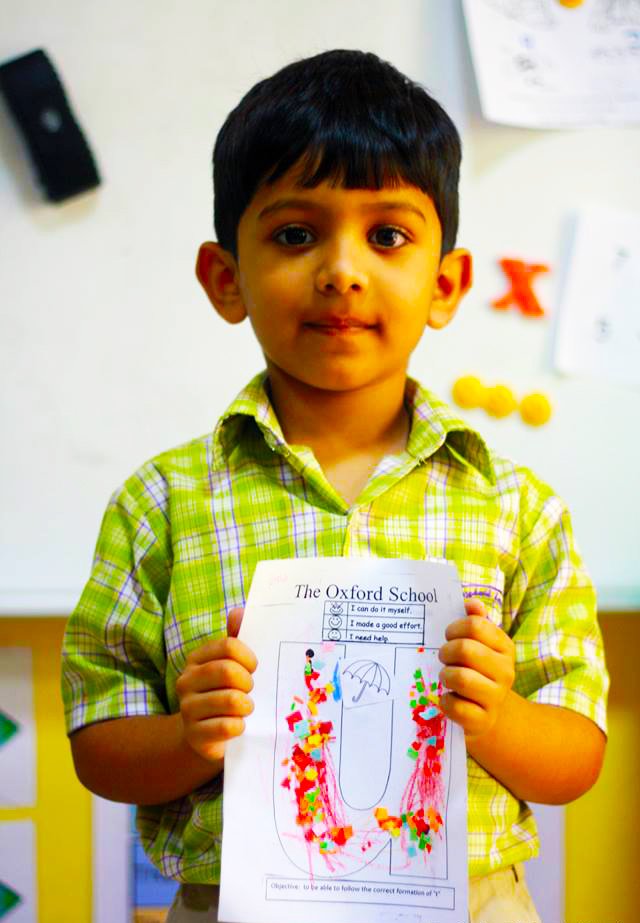 Ein kleines Kind an der Oxford School Dubai zeigt Stolz auf seine Arbeit