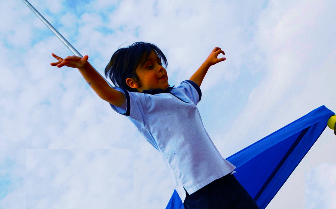 Bild zeigt ein kleines Kind, das sich amüsiert, während es in einem Test des Mutes, der Konzentration und der körperlichen Geschicklichkeit balanciert
