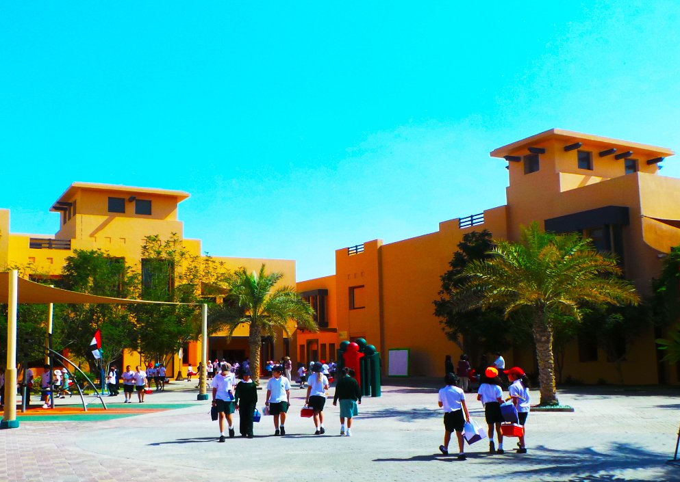 Raha International School building entrance with children leaving and entering the main reception