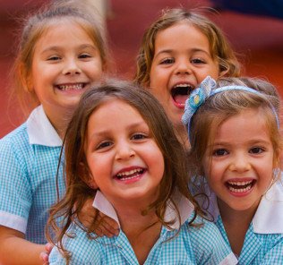 Bild zeigt lachende, glückliche jüngere Kinder in Uniform an der British International School Abu Dhabi