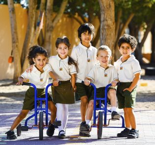 صورة لأطفال صغار في مدرسة غرينفيلد المجتمعية في الغابة ، اثنان منهم على دراجة ثلاثية العجلات