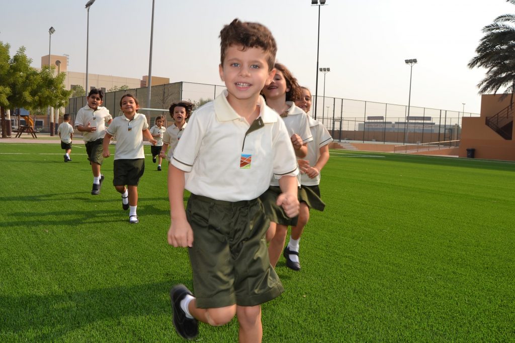 Auf diesem Foto erkunden unsere Schüler der 1. Klasse ihren Campus, indem sie über den Fußballplatz der Grundschule laufen.