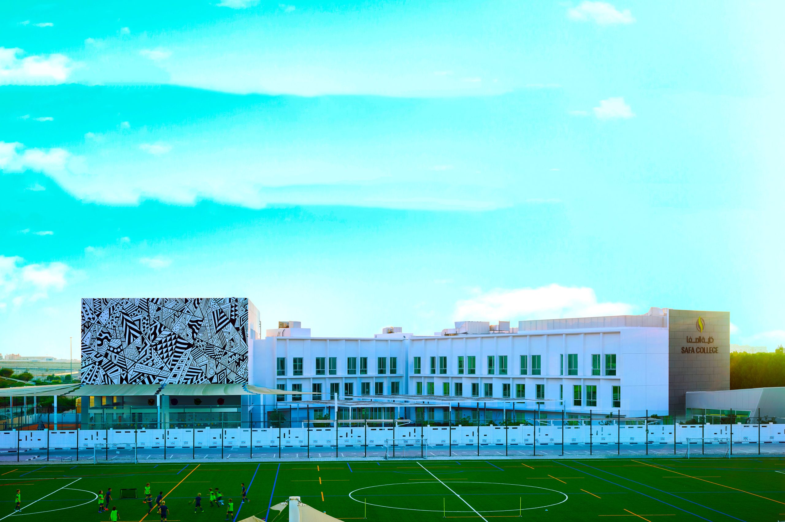 Foto der Safa Community School, das das neue sechste Zentrum mit Sportplätzen im Vordergrund hervorhebt.
