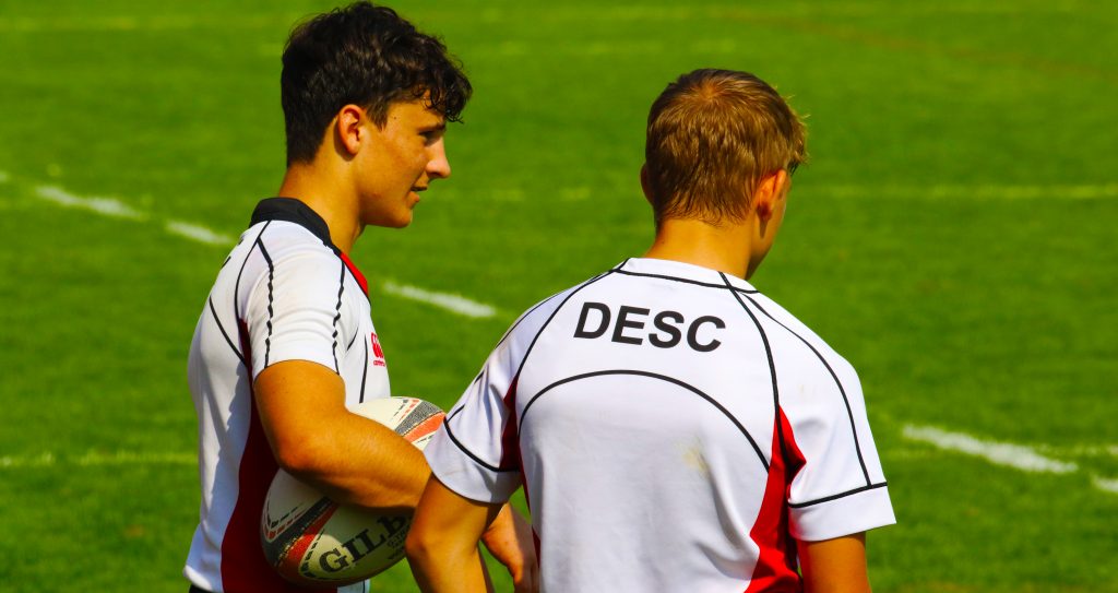 Photograph of players from the DESC Rugby Team at the Dubai College 10s in Dubai celebrating after winning an historic clean sweep in the "beautiful game"