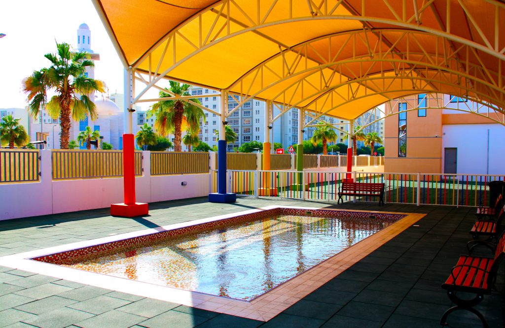 Wunderschönes Mosaik-KG-Schwimmbad an der Schule der Dubai International Academy in Dubai, das die schattige Umgebung hervorhebt, um jüngere Kinder vor der Sonne zu schützen