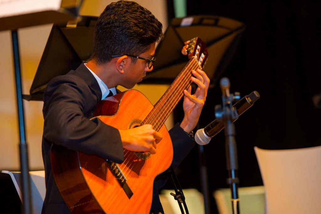 يتم عرض تدريس الموسيقى في برايتون كوليدج أبوظبي هنا من قبل طالب يعزف على الجيتار الكلاسيكي كجزء من الأوركسترا