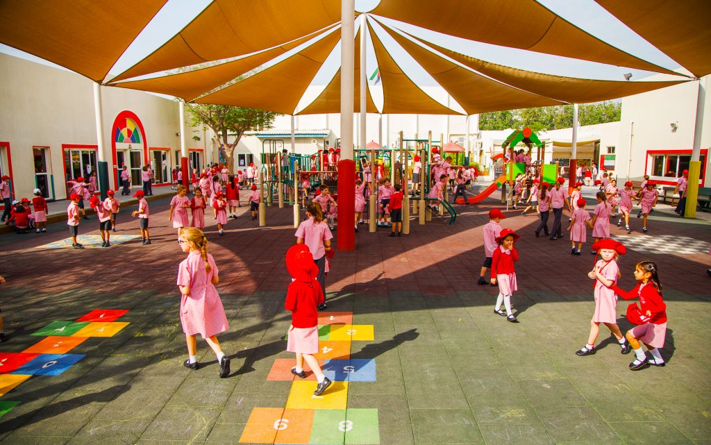 Foto von DESS-Kindern der englischsprachigen Schule in Dubai beim Spielen auf dem zentralen Spielplatz der Schule. Die Klassenräume und Einrichtungen der Schule sind im Hintergrund zu sehen.