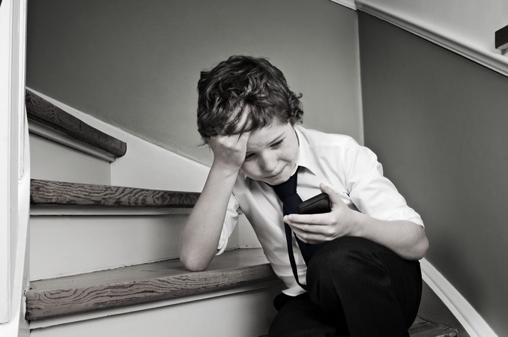 Online-Mobbing- und Cyber-Mobbing-Leitfaden für Eltern mit Ratschlägen, was zu tun ist. Foto zeigt gemobbtes Kind in Verzweiflung.