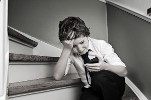 Online bullying and cyber-bullying guide for parents with advice on what to do. Photo shows bullied child in despair.
