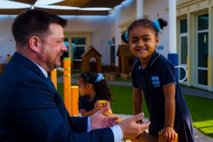 Photograph of Rob Commons, Principal of Uptown International School in Dubai, helping a PYP student